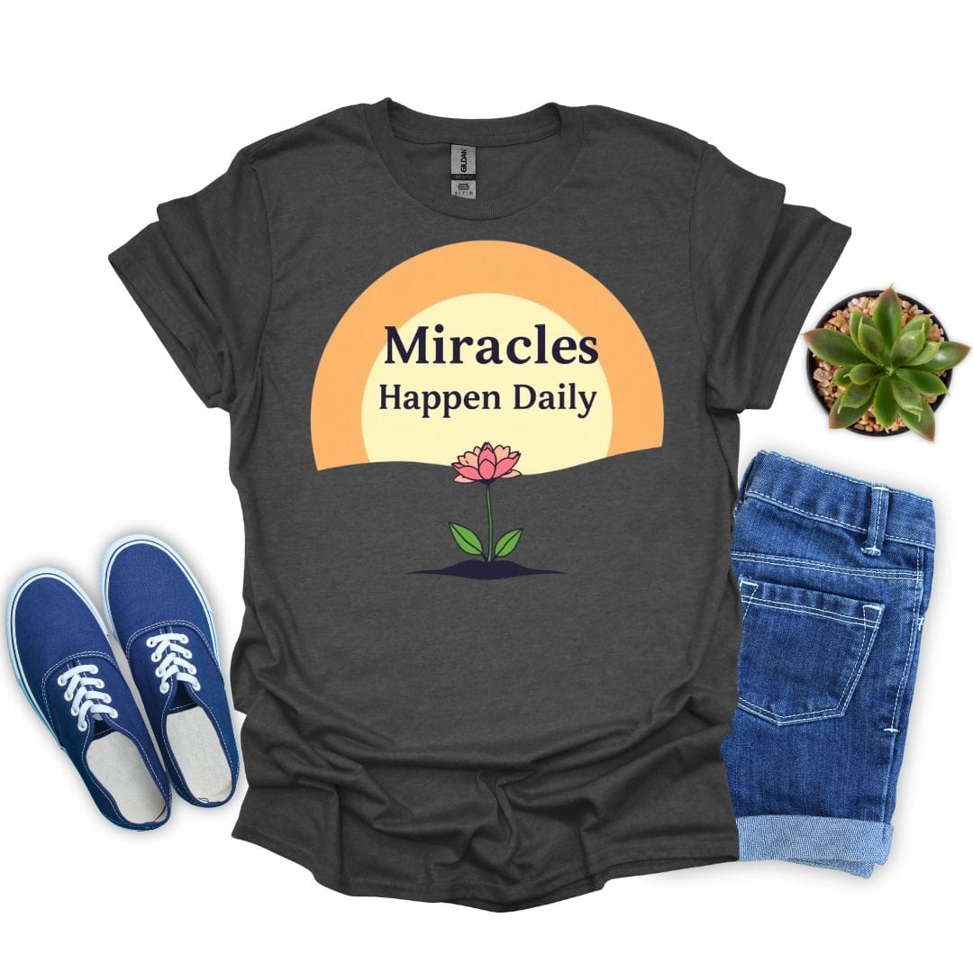 Dark heather t-shirt with 'Miracles Happen Daily' graphic, blue sneakers, rolled jeans, and a plant on a white background.