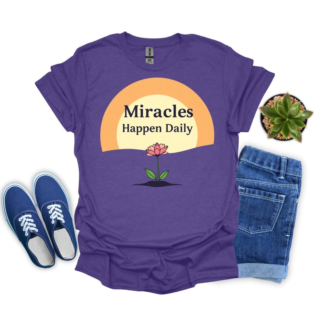 Heather purple t-shirt with 'Miracles Happen Daily' design, blue sneakers, denim shorts, and a plant on a white background.
