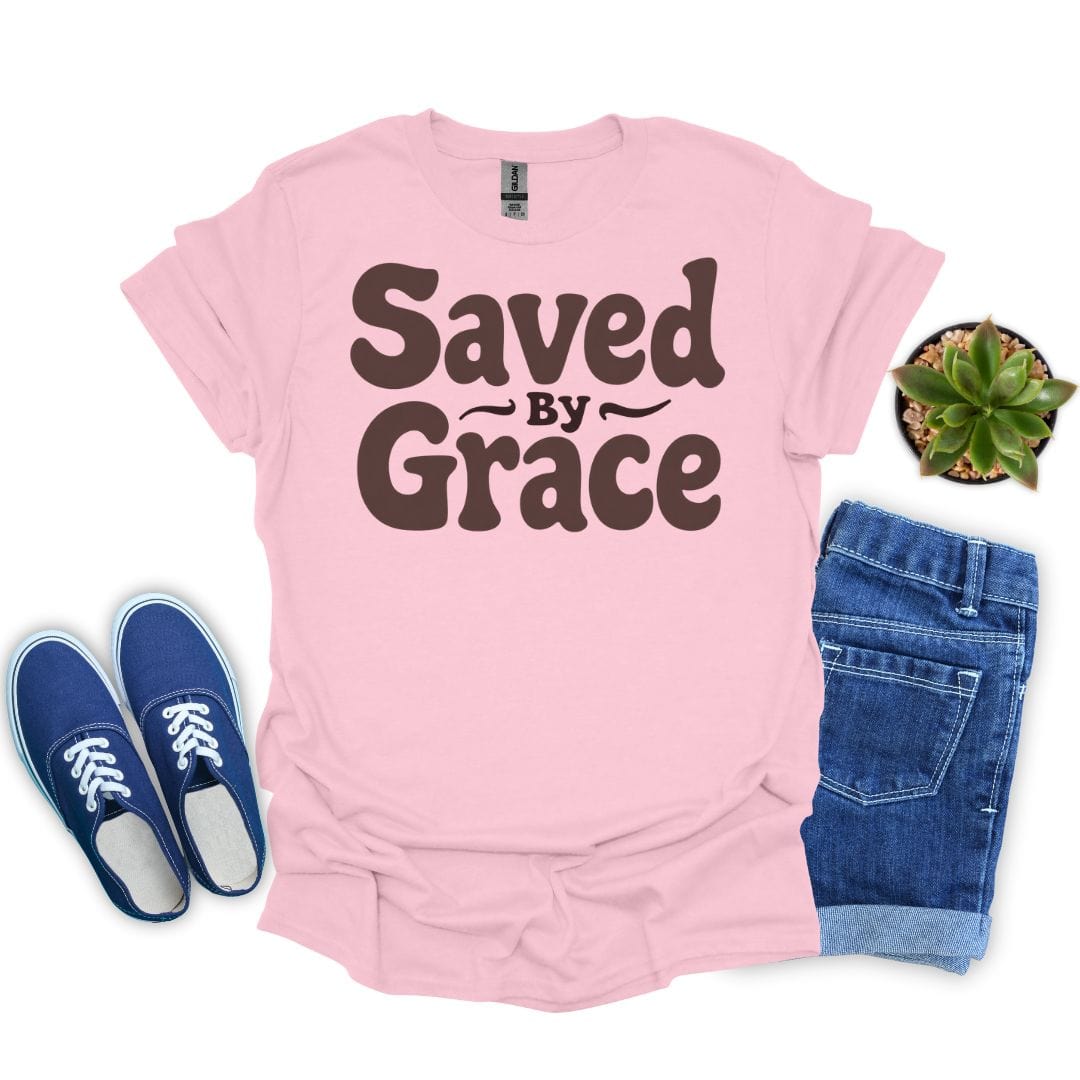 Light pink t-shirt with 'Saved by Grace' text, blue sneakers, denim shorts, and a plant on a white background