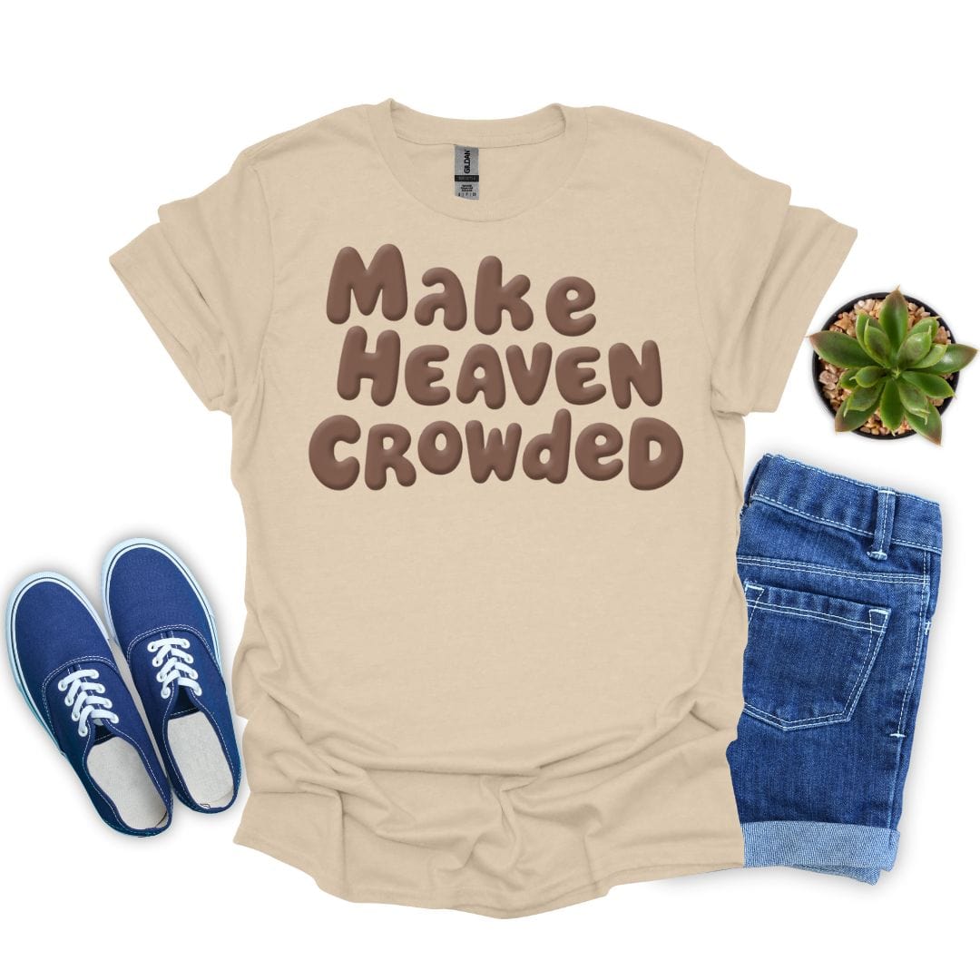 Sand t-shirt with 'Make Heaven Crowded' text, blue sneakers, denim shorts, and a plant on a white background