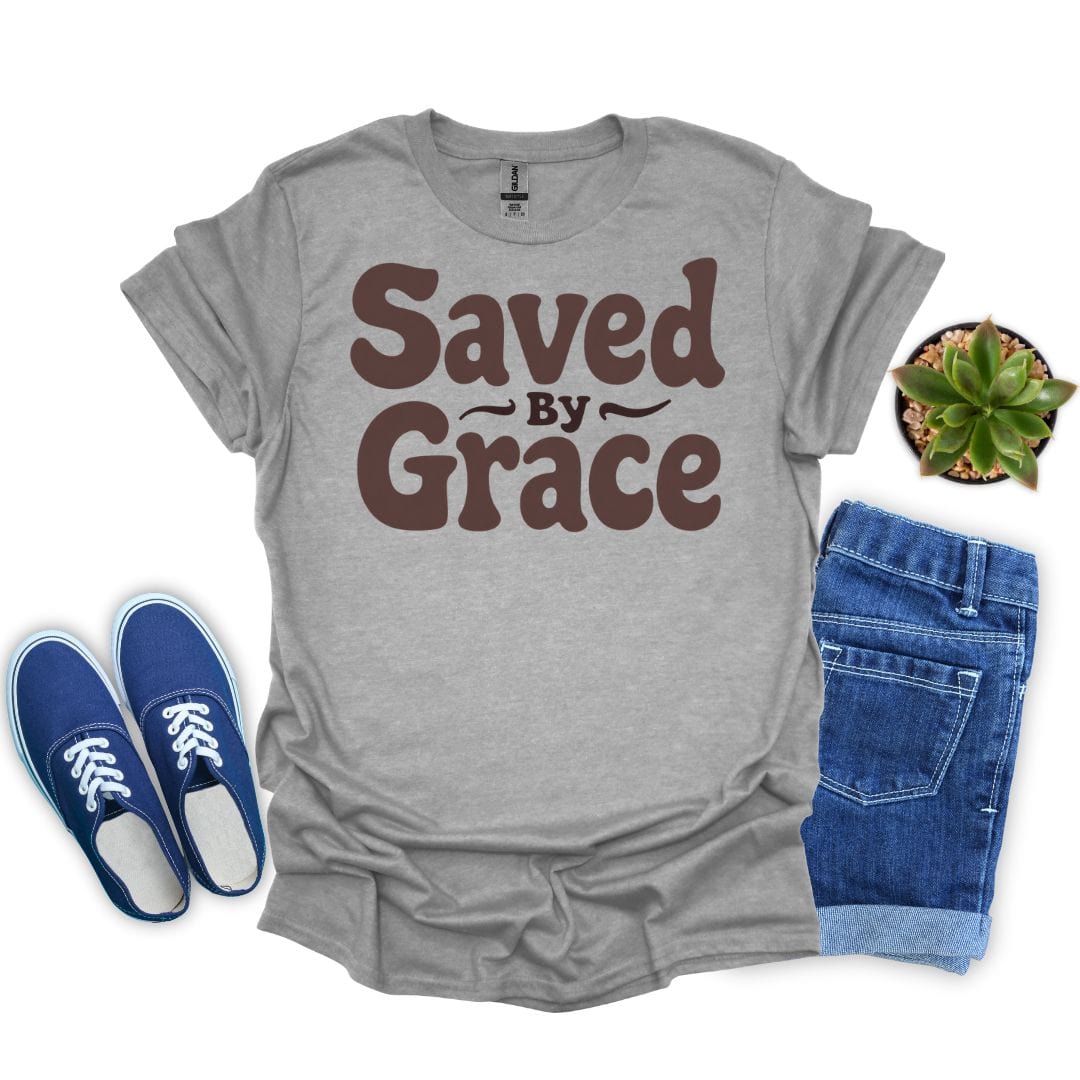 Sport gray t-shirt with 'Saved by Grace' text, blue sneakers, denim shorts, and a plant on a white background