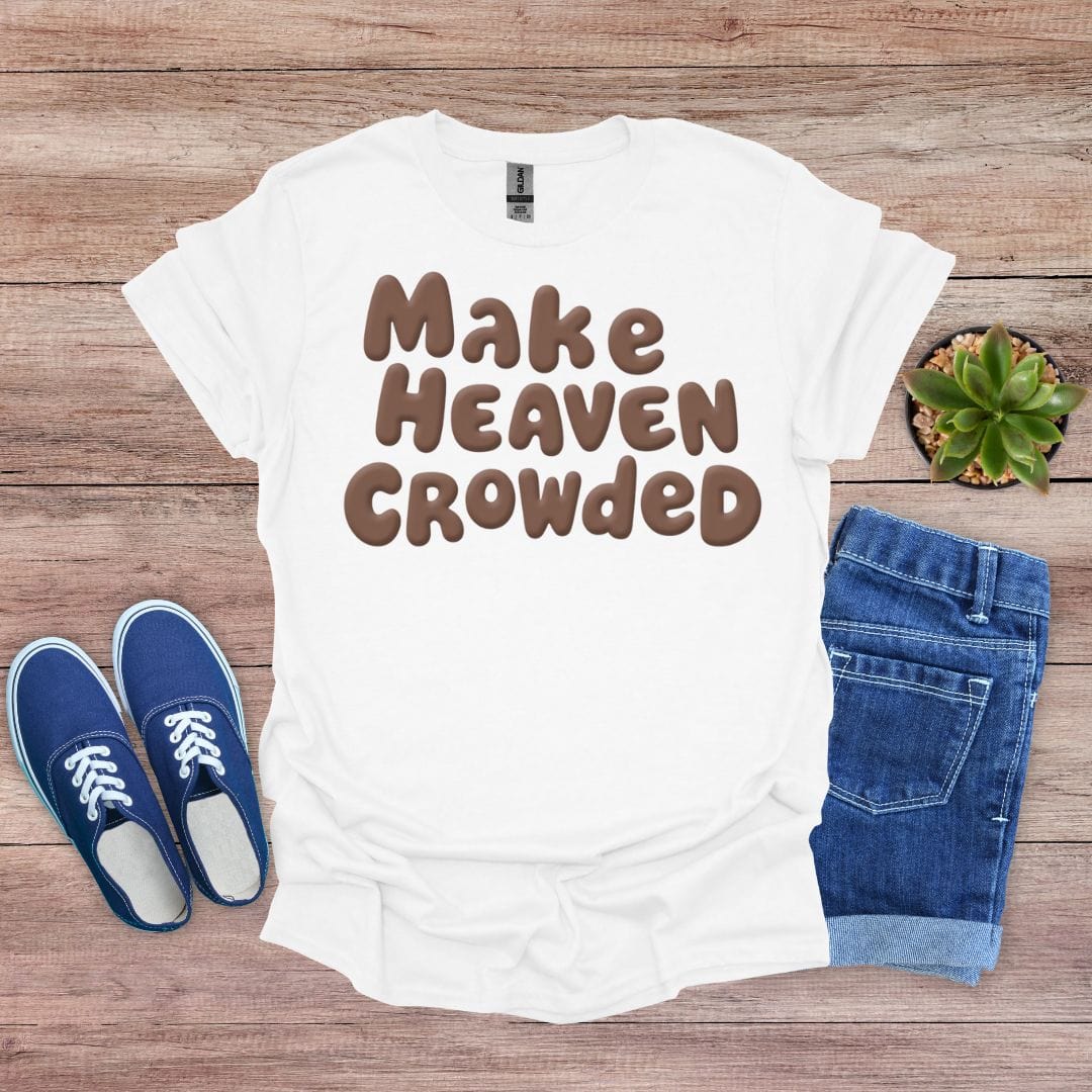 White t-shirt with 'Make Heaven Crowded' text, blue sneakers, and jeans on a wooden surface.